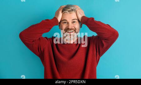 Ein emotional erwachsener Mann, der seinen Kopf blau berührt Stockfoto