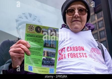 London, Großbritannien. 26. April 2023. Ein Umweltaktivist hält während eines Protests vor der Jahreshauptversammlung des größten Bioenergielieferanten des Vereinigten Königreichs Drax ein Flugblatt. Die britische Energieregulierungsbehörde Ofgem untersucht derzeit die Einhaltung der Nachhaltigkeitsvorschriften durch Drax unter zunehmender Prüfung seiner Tätigkeiten, einschließlich der Holzquelle und der Beschreibung des zur Stromerzeugung eingesetzten Verfahrens als „CO2-neutral“. Staatliche Subventionen für Biomasse an Drax werden voraussichtlich 2027 auslaufen. Drax hat heute seinen bisher höchsten Jahresumsatz mit 731m Mio. £ gegenüber 398m Mio. £ im Vorjahr bekannt gegeben. Kredit: Mark Stockfoto