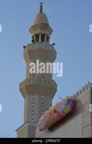 Hintergrund für Festlichkeiten und Feiern vor einer Moschee in Kairo Ägypten mit Dutzenden von Ballons auf dem Dach der Moschee neben dem Minarett, das geworfen werden soll Stockfoto