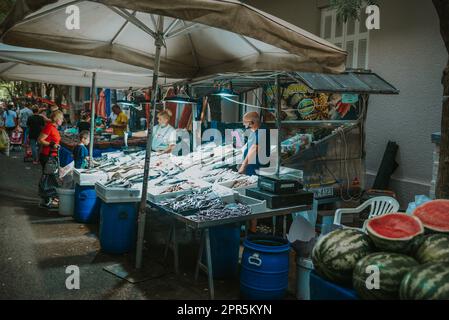 Fish Monger verkauft den Fang des Tages unter Blitzlichtern auf dem europäischen Bauernmarkt in Athen Stockfoto