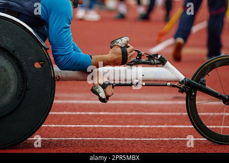 Nahaufnahme Rennrollstuhl mit männlichem Sportler, Hände in Rennhandschuhen, Sommer-Para-Athletik-Meisterschaften Stockfoto