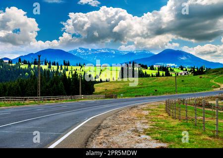 Der Highway liegt in den hohen Bergen mit schneebedeckten Gipfeln. Stockfoto