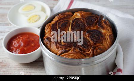 Kubaneh – Jemenitisches jüdisches Brot, Brioche-Brot – wird am Shabbat-Morgen serviert, serviert mit einem Dip aus zerkleinerten Tomaten und hart gekochten Eiern Stockfoto