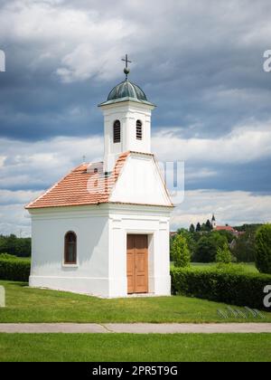 Kleine Kirche auf grünem Feld in ländlicher Frühlingslandschaft, Burgenland, Österreich Stockfoto