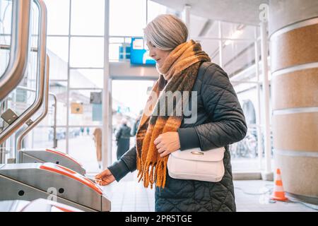 Ältere Frau ermöglicht Fahrkarte, um den Zug zu nehmen Stockfoto