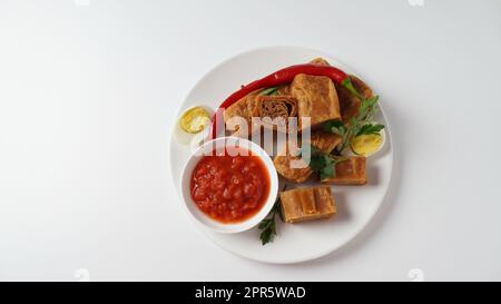 Jachnun oder Jahnun, jüdisches Gebäck aus dem jemenitischen Raum, serviert mit frischer geriebener Tomate und gekochtem Ei und Zhug, die von den Adeni-Juden stammen, und traditionell serviert am Sabbat-Morgen in Israel. Stockfoto