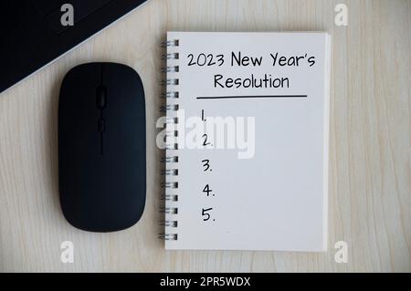 Neujahrsvorsätze 2023 Text auf Notizblock mit Maus und Laptop auf Holzschreibtisch. Ein neues Konzept Stockfoto