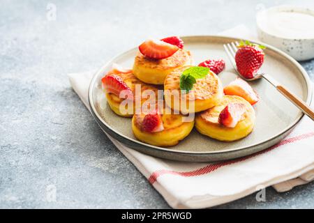 Hüttenkäse-Pfannkuchen, Ricotta-Fritters oder Syrniki mit Minze und Erdbeeren. Gesundes und köstliches Frühstück am Morgen. Stockfoto