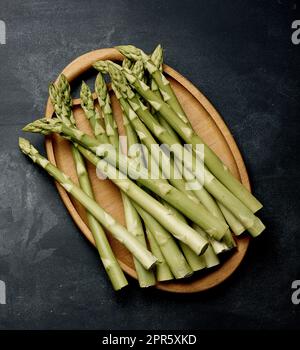 Ein paar frische, rohe Spargel auf einem schwarzen Holzbrett, ein gesundes Produkt Stockfoto