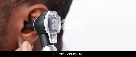 Arzt untersucht das Ohr des männlichen Patienten Stockfoto