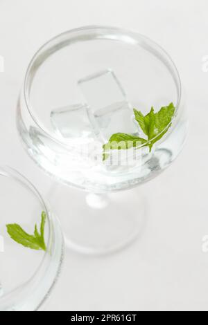 Transparenter Cocktail mit Eiswürfeln in einem Glas, dekoriert mit Minzblättern aus nächster Nähe Stockfoto