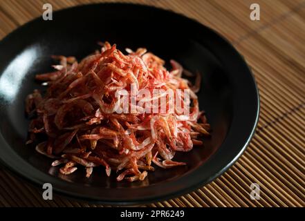 Getrocknete Sakura-Garnelen auf einem Teller auf einer Bambus-Lunch-Matte. Stockfoto