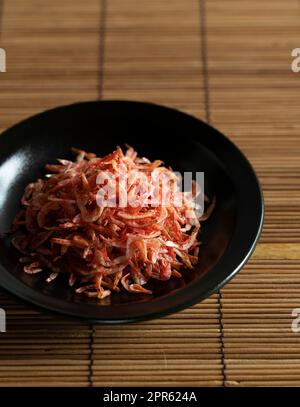 Getrocknete Sakura-Garnelen auf einem Teller, der auf einer Bambusluncheon-Matte platziert wurde. Das Bild des japanischen Essens. Stockfoto