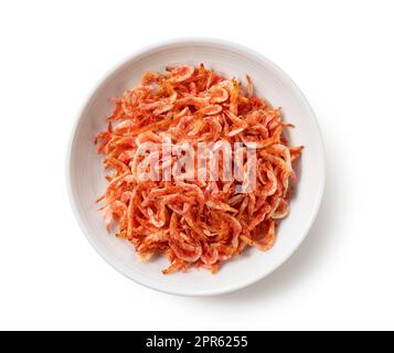 Getrocknete Sakura-Garnelen auf einem Teller auf weißem Hintergrund. Stockfoto