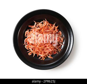 Getrocknete Sakura-Garnelen auf einem Teller auf weißem Hintergrund. Stockfoto