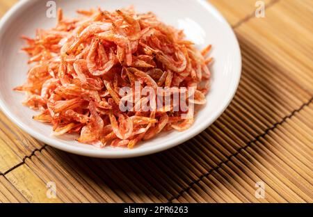 Getrocknete Sakura-Garnelen auf einem Teller, der auf einer Bambusluncheon-Matte platziert wurde. Bild von japanischem Essen. Stockfoto