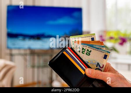 Die Hand eines Mannes, der eine Geldbörse mit europäischen Banknoten und Plastikkarten hält. Nahaufnahme. Stockfoto