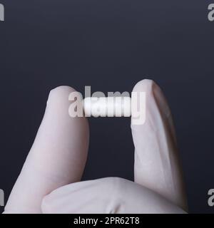 Handschuhe in der Hand, die eine Kapsel hält Stockfoto