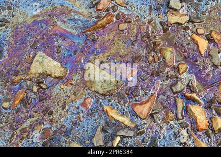 Farbenfroher Kraftstoff und Öl auf Asphaltstruktur mit starker Umweltverschmutzung. Stockfoto