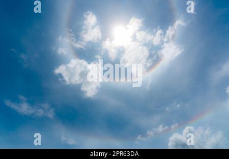 Sun Halo oder ein regenbogenfarbener Ring um die Sonne. Sonniger Himmel mit Sonnenhimmel. Optisches Phänomen, das durch Licht erzeugt wird. Cirrus- oder Cirrostratuswolken in der Troposphäre mit Lichtbrechung und Reflexion. Stockfoto