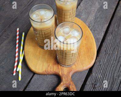 Sommergetränk Eiskaffee in hohem Glas auf rustikalem Holzhintergrund. Selektiver Fokus, Draufsicht Stockfoto