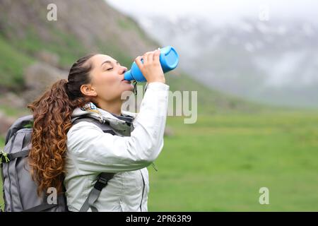 Trekker trinkt Wasser aus der Kantine im Berg Stockfoto