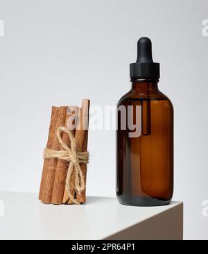 Braune Glasflasche mit Pipette auf grauem Hintergrund. Behälter für Kosmetika Stockfoto