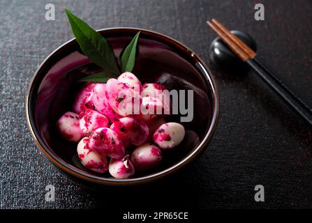 Eingelegter Shiso-Knoblauch, serviert auf einem Teller auf schwarzem Hintergrund. Stockfoto