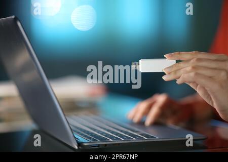 Eine Frau, die nachts zu Hause einen USB-Stick in der Hand hält Stockfoto