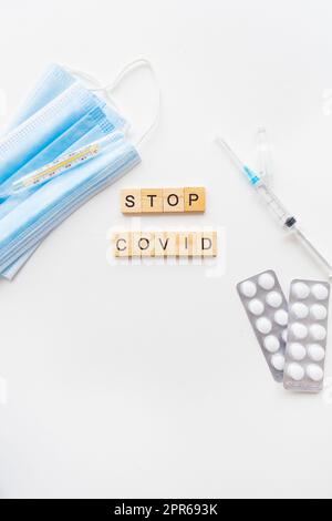 Stoppt die Coronavirus-Inschrift. Vorbereitung zur Impfung gegen Covid-19. Spritze, Impfstoff, Pillen, medizinische Maske. Stockfoto