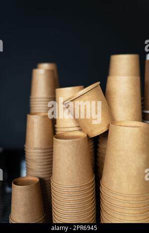 Einweg-Pappbecher auf schwarzem Hintergrund in einem Café. Barista arbeiten. Das Konzept, Kaffee zu kochen, Kaffee zum Mitnehmen. Stockfoto