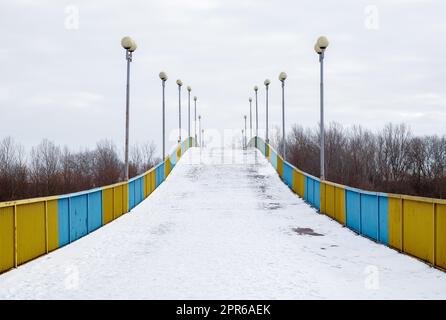 Fußgängerbrücke in Tschernihiv über den Fluss Desna im Schnee an einem Winterschneetag. Stockfoto