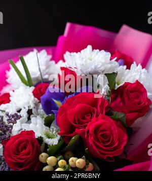 Nahaufnahme eines bunten Blumenarrangements aus verschiedenen Blumen. Original schöner heller Strauß mit roten Rosen, weißer Chrysantheme Stockfoto