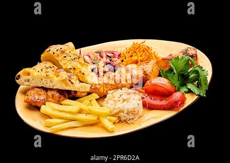 Auf einem Teller mit Pommes frites auf einem schwarzen isolierten Hintergrund wird saftiger Shish-Kebab aus Hühnerfilet gelegt, Tawuk nähen Stockfoto