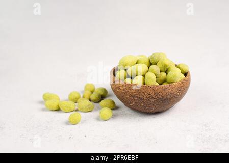 Haufen grüner Wasabi-beschichteter Erdnüsse in einer Schüssel, würziger Snack, orientalisches Essen Stockfoto