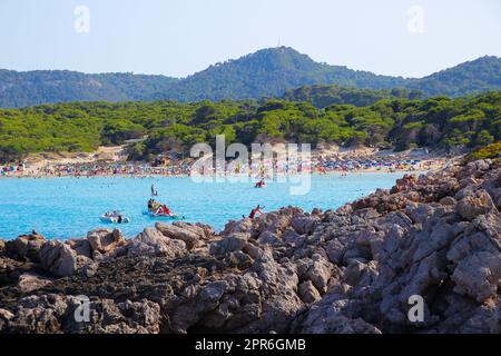 Touristenmassen auf Urlaub am Mittelmeer, versammelt am Strand von Cala Agulla an der Küste von Mallorca auf den Balearen Stockfoto