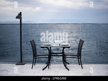 Fantastisches romantisches Abendessen am Strand. Romantik und Liebe, Esstisch mit Meerblick an bewölkten Tagen. Stockfoto