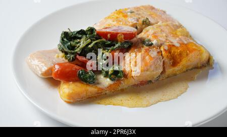 Lachsfilet mit Spinat und Kirschtomaten in cremiger Sauce Stockfoto