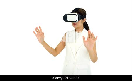 Asiatische Frau in weißem Kleid mit Virtual-Reality-Brille, spielen ein interaktives Spiel. Konzept Der Zukunftstechnologie. Stockfoto