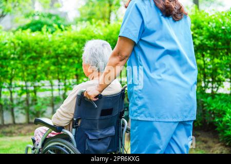 Pfleger Hilfe asiatische ältere Frau Behinderung Patient sitzt im Rollstuhl im Park, medizinisches Konzept. Stockfoto