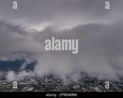 Fliegen durch dicke Wolken. Regenwolken am Himmel. Kumuluswolken, Meteorologie und Klimastudien. Video der Stadt aus der Höhe der Wolken, Luftaufnahmen. Quadcopter, Drohne Stockfoto