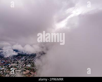 Fliegen durch dicke Wolken. Regenwolken am Himmel. Kumuluswolken, Meteorologie und Klimastudien. Video der Stadt aus der Höhe der Wolken, Luftaufnahmen. Quadcopter, Drohne Stockfoto