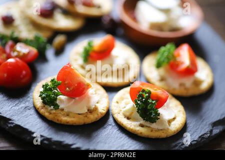 Vorspeisen und Snacks, Cracker, getrocknete Früchte, Tomaten, Petersilie, Und Frischkäse Stockfoto