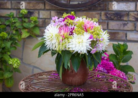 Strauß Dahlien in einer Vase auf einem Gartentisch Stockfoto