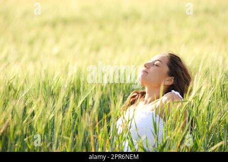 Entspannte Frau, die auf einem Feld sitzt und atmet Stockfoto