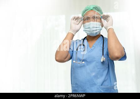 Asiatischer Arzt trägt Maske, Gesichtsschutz und PSA-Anzug neu auf weißem Hintergrund isoliert mit Clipping Pfad zum Schutz der Sicherheit Infektion Covid19 Coronavirus. Stockfoto