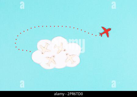 Flugzeuggruppe, die in einer Wolke fliegt, rotes Flugzeug denkt anders und nimmt die entgegengesetzte Richtung, gegen den Fluss symbolisch, Mut und Siegerkonzept Stockfoto