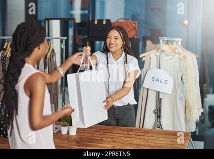 Sie glaubt an die Unterstützung lokaler Geschäfte. Eine kleine Aufnahme eines jungen Ladenbesitzers, der einem Kunden ein Paket über den Ladentisch übergab. Stockfoto