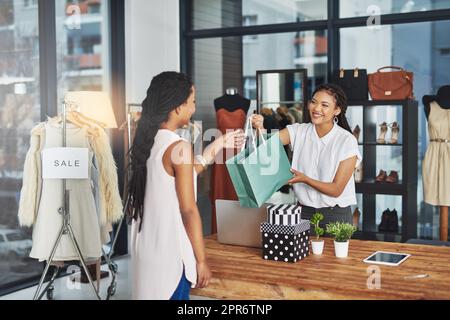 Im Zweifelsfall einkaufen. Eine kleine Aufnahme eines jungen Ladenbesitzers, der einem Kunden ein Paket über den Ladentisch übergab. Stockfoto