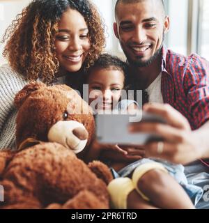 Einige Momente sind zu gut, um sie nicht festzuhalten. Eine Aufnahme einer glücklichen, jungen Familie von drei Kindern, die zusammen Selfies in ihrem Wohnzimmer zu Hause machen. Stockfoto